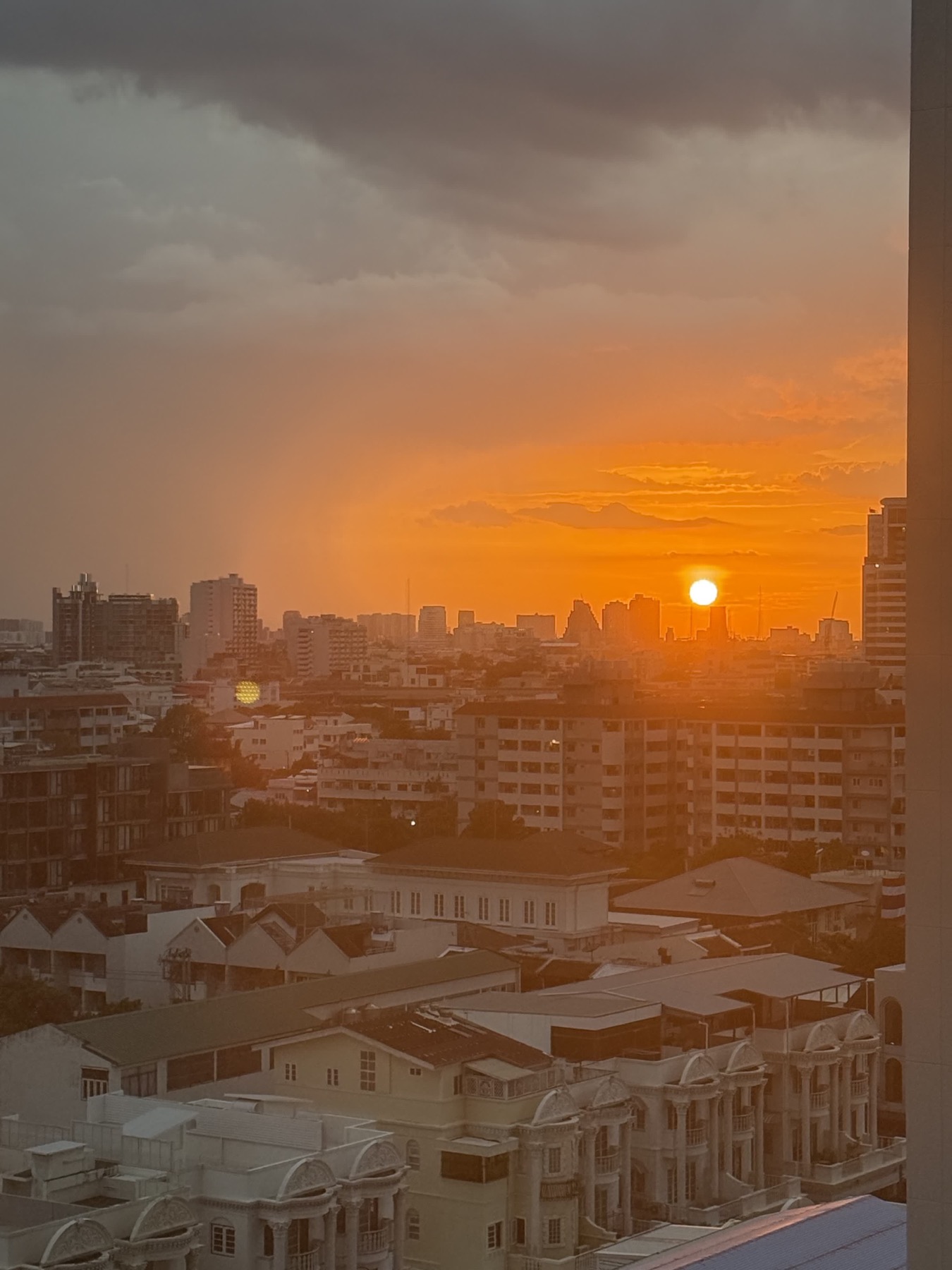 A dramatic sunset beneath storm clouds over Bangkok