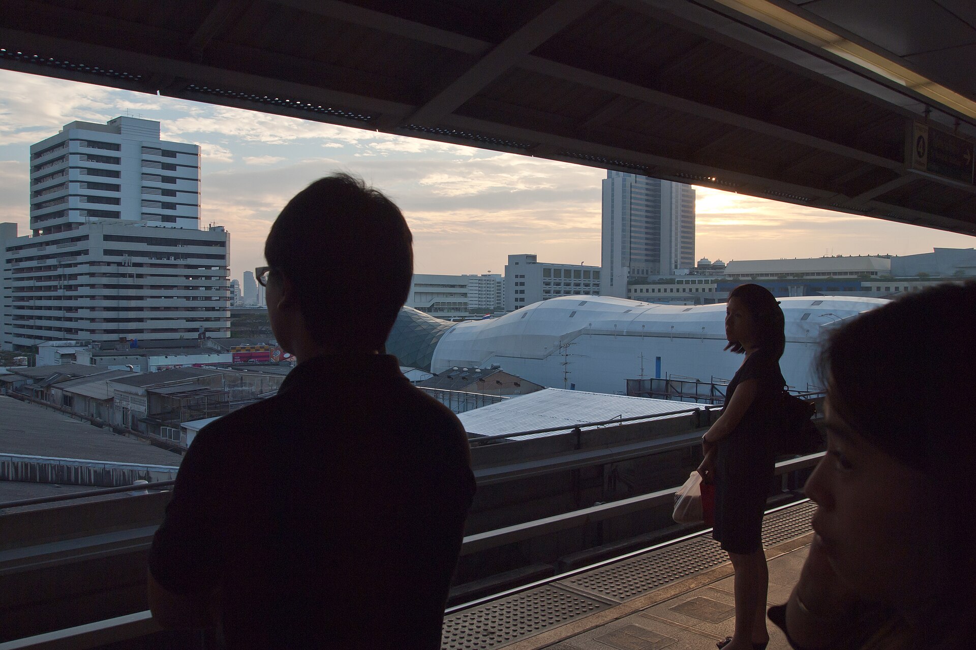 Commuters waiting at Siam BTS station with central Bangkok in the background