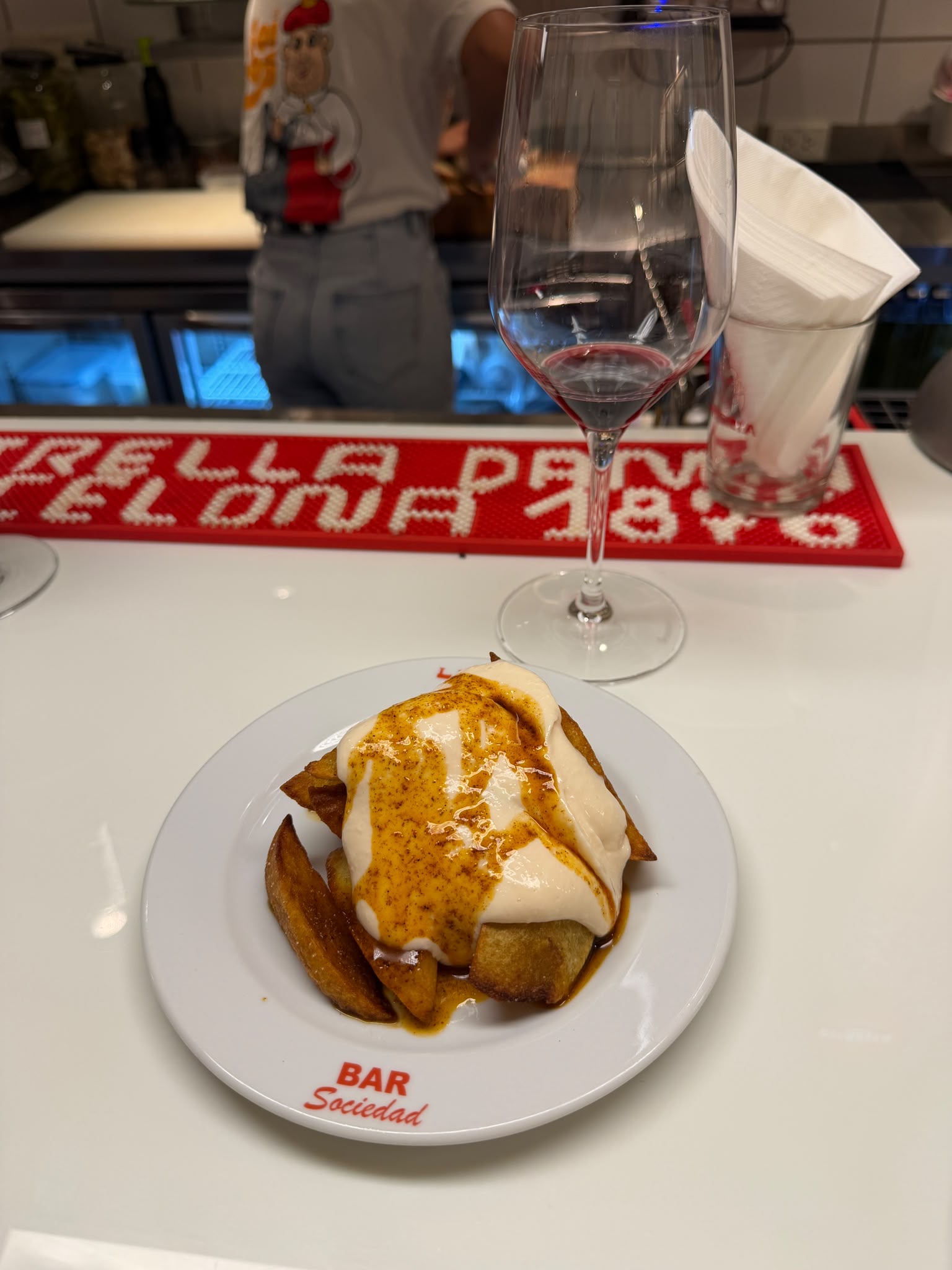 Glass of red wine beside a potato dish at Bar Sociedad Laferia